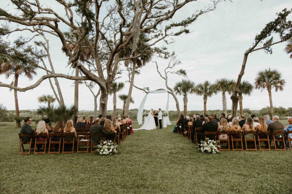 Bride and groom laughing beneath an oak tree at the Fountain of Youth in St. Augustine